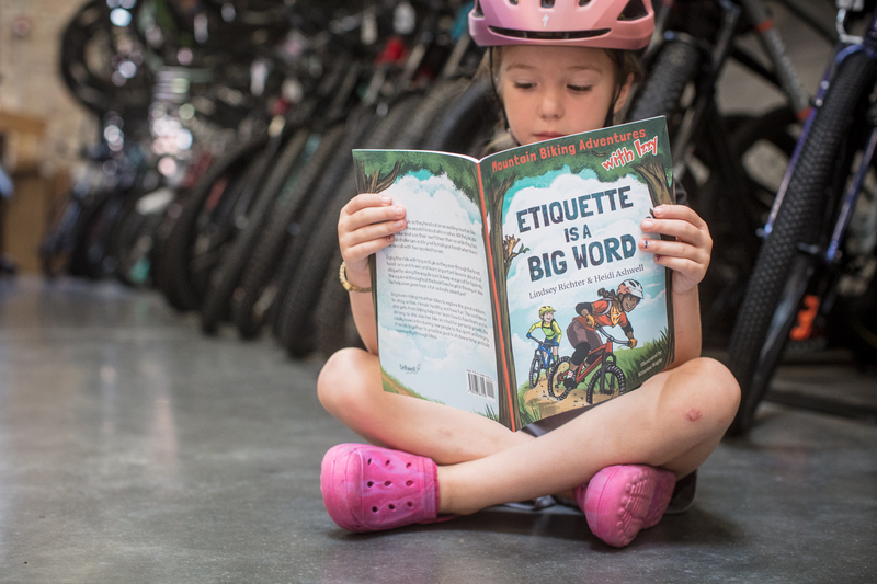 "Youth rider reading Lindsey's book "Mountain Biking Adventures with Izzy: Etiquette is a Big Word.""