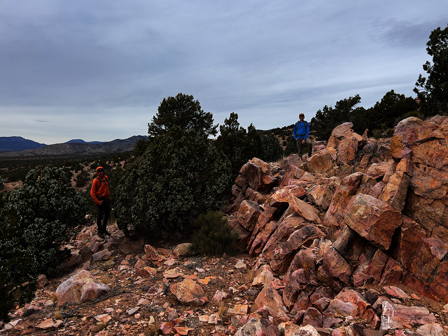 "Two men standing in a desert rock garden smiling to camera."