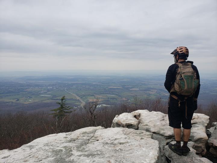 Rich Edwards, riding, cliff, view of town, helmet, Five Tens, backpack