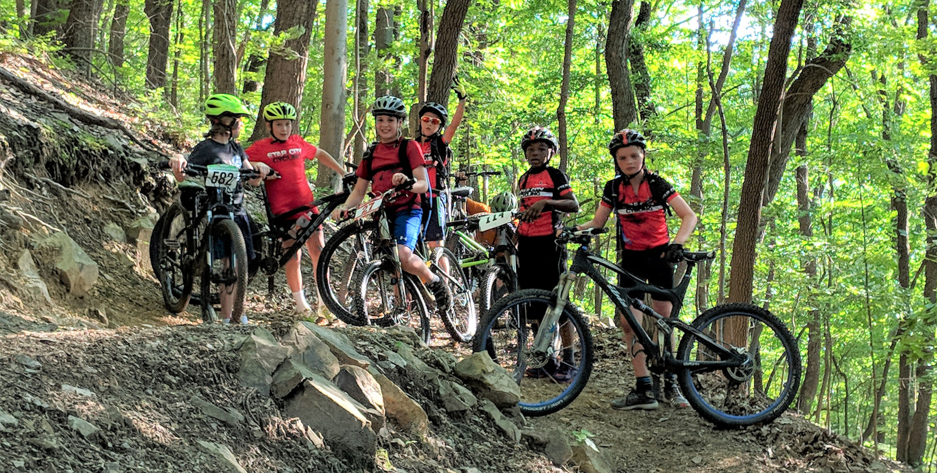 a group of youth mountain bikers pose on the trail for a photo