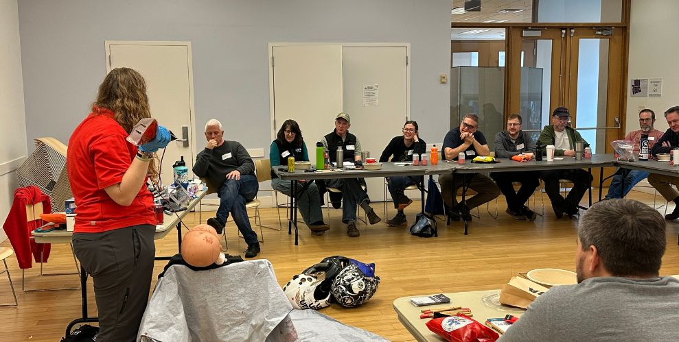 MTB First Aid Course with students watching teacher in center of room.