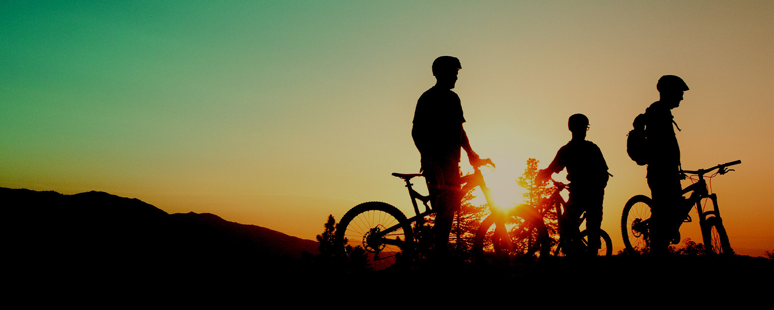 a group of three riders' silhouettes with sunset in the background