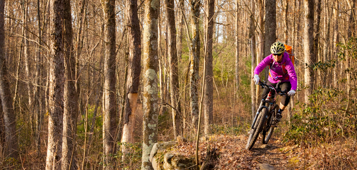 Person riding mountain bike on local mountain bike trail, connect with IMBA staff to learn more about the trail development self assessment