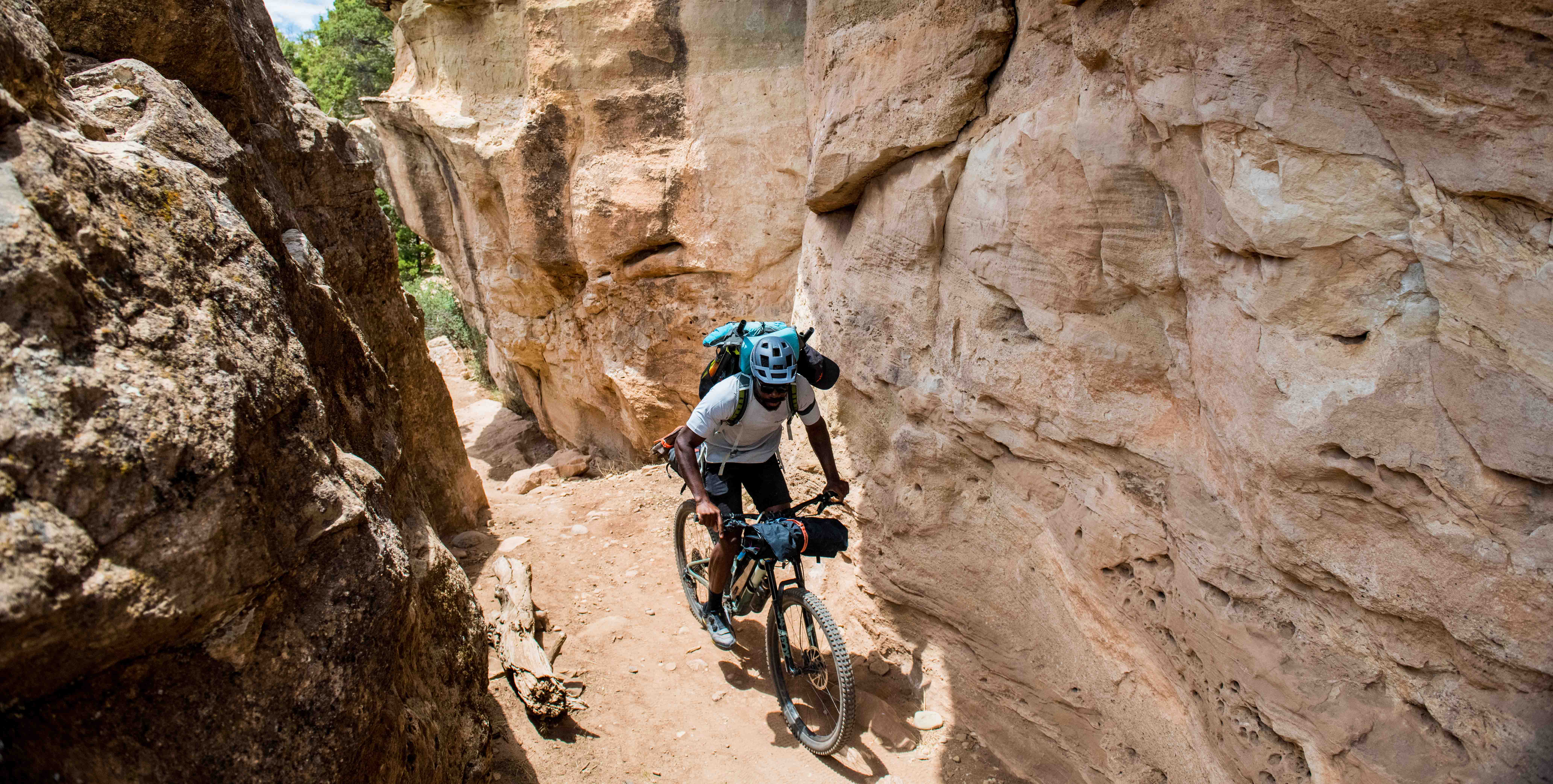 Mountain biker with packs and panniers riding through a slot canyon
