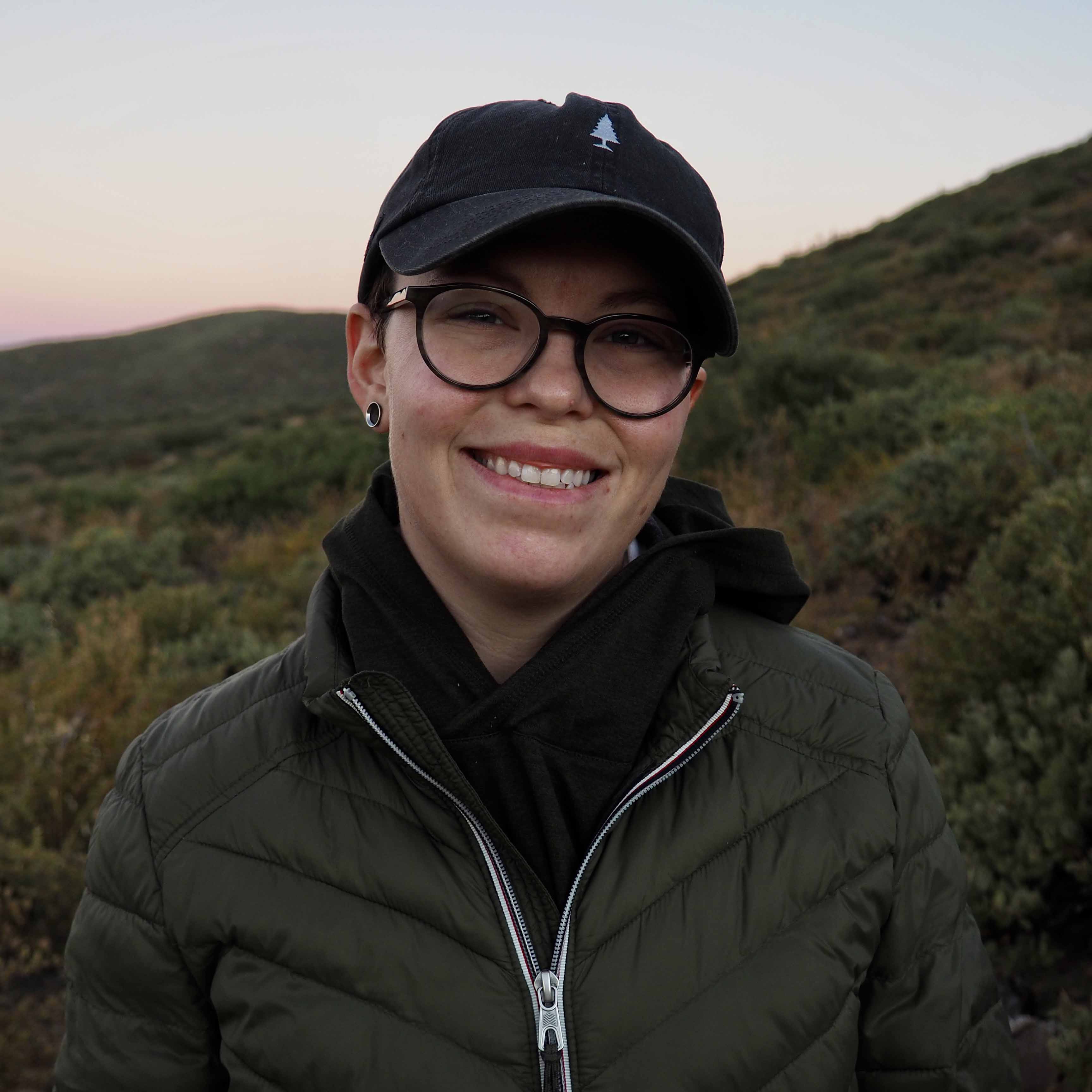Lea outside in a black hat at sunset