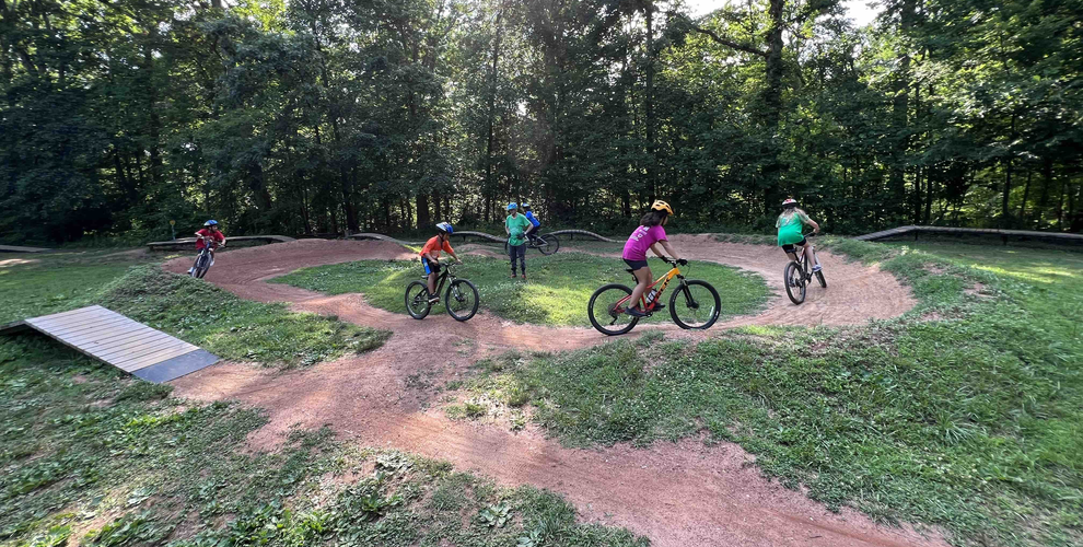 Youth riders doing laps on a dirt pump track in Brookfield Park