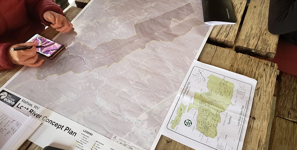 A concept map of Lost River State Park and hands holding a smartphone with a  topographic map on screen. 