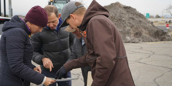 four people huddling around a map outside