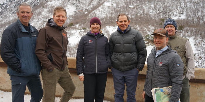 six white people smiling for camera in winter outfits