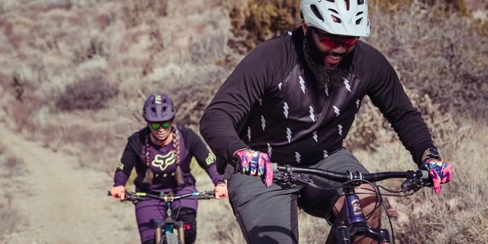 Two people smiling riding mountain bikes on trail