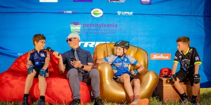 NICA riders from Pennsylvania on inflatable couch, speaking into microphone. 