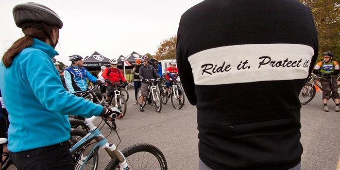 Ride it. Protect it. on the back of a male mountain biker's jacket. 