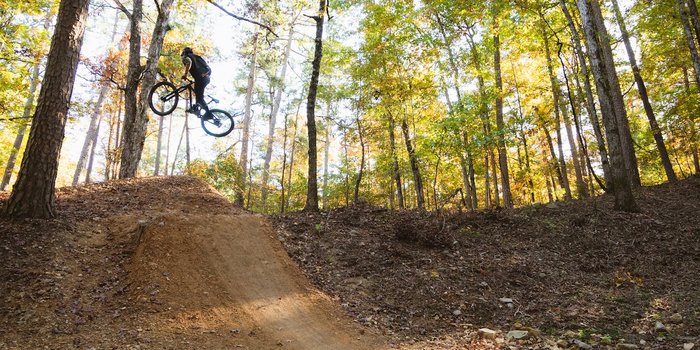 Mountain biker in air after high jump from dirt single track in Northwoods, Arkansas.