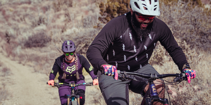 Two people smiling riding bikes on trails