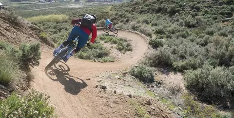 Two eMTB riders on downhill bermed trail