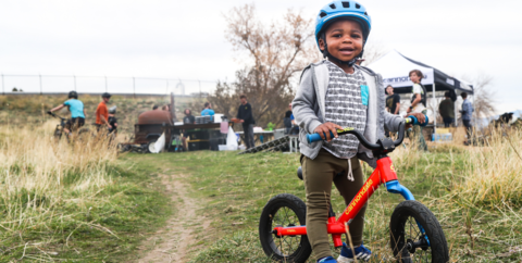 Little boy on balance bike in front of MTB club event.