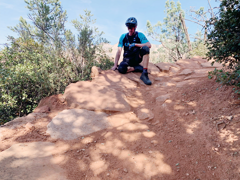 Joey Klein kneels next to an 11 year old armored berm turn in Sedona, AZ.
