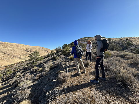 A group of people are gathered and looking into a desert landscape