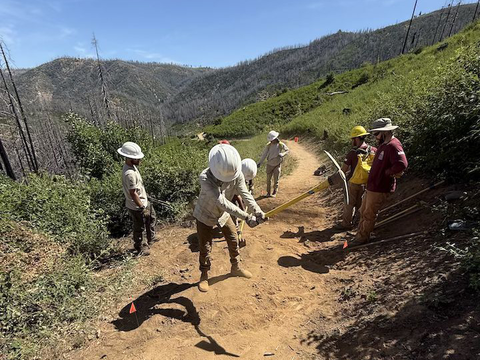 Members of the trail care school use tools to create a rolling grade dip