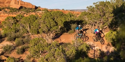 Two people riding mountain bike trails that are supported by donations