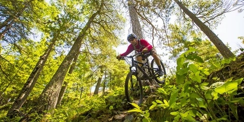 person riding downhill on mountain bike trail