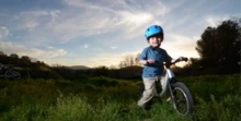 Child riding a balance bike in a field