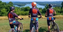 Three mountain bikers wearing a BAMBA jersey overlooking the Blue Marsh Lake