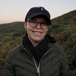 Lea outside in a black hat at sunset