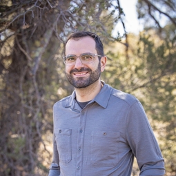 man with glasses wears a grey collared shirt