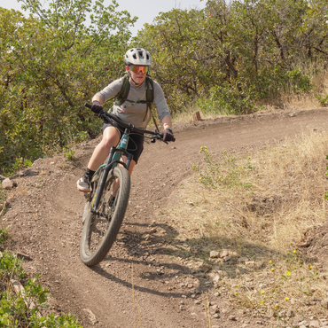 Lea riding a mountain bike around a bermed corner