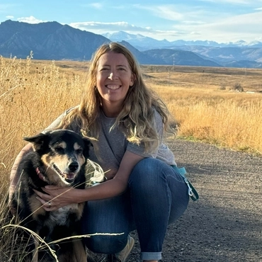 Dr. Jen Caragol sitting with her dog Maggie, smiling like a mountain biking momma!