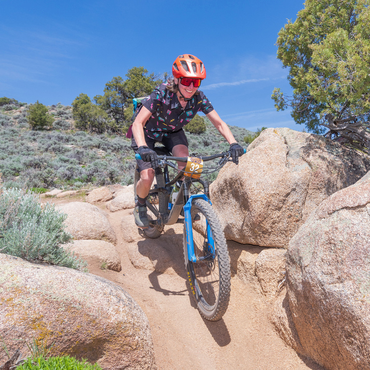 riding a black bike with a blue fork in a rocky, arid environment