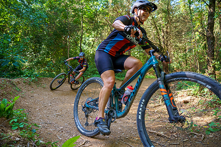 Two adults ride through a berm.