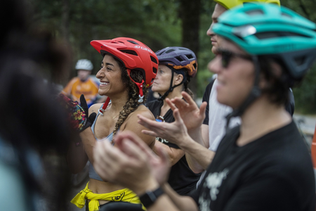 Mountain bikers gathered, smiling and clapping for a trail system grand opening. 